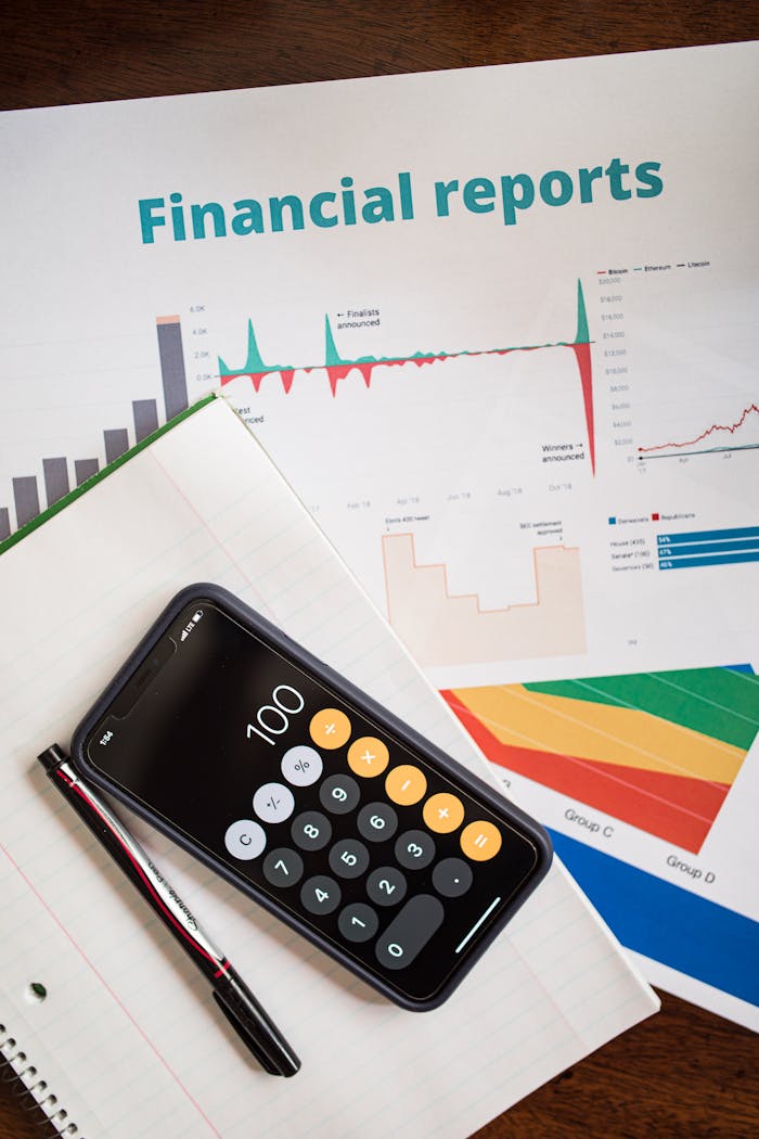 Top view of financial reports with a calculator app open on a smartphone.